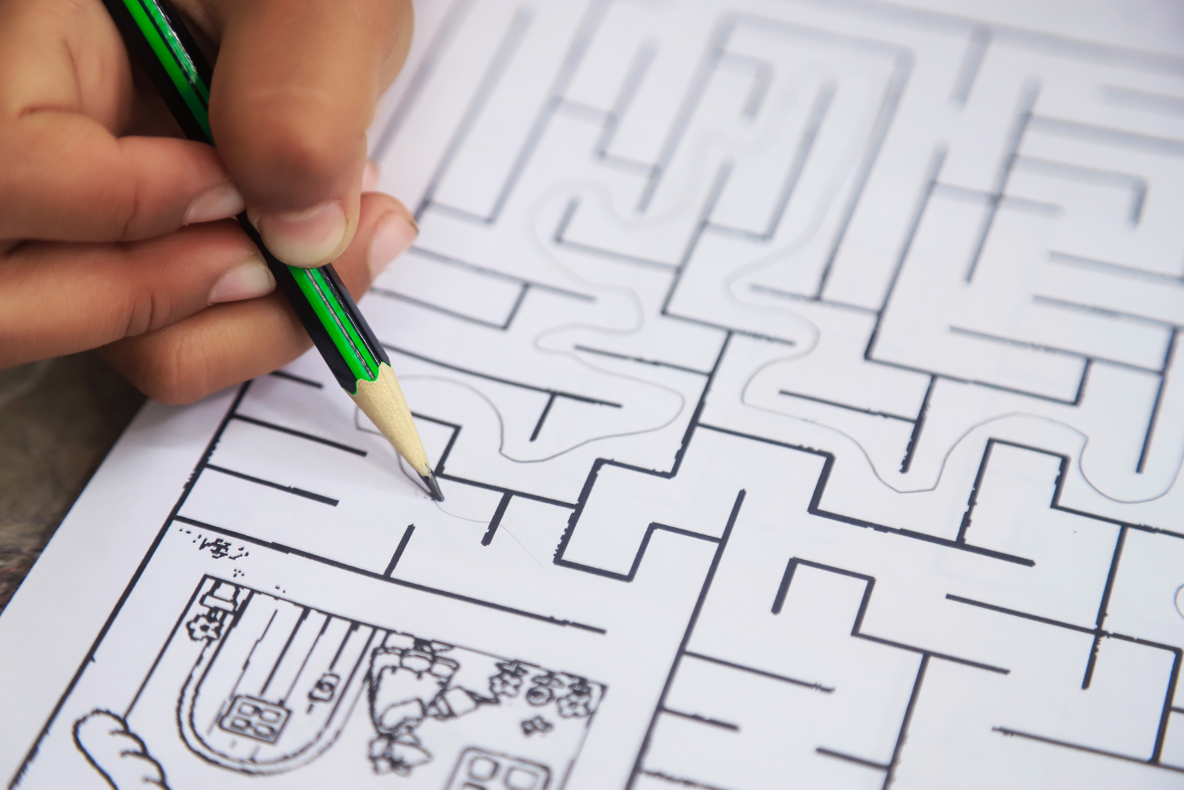 kid hand with pencil doing maze line game for learning and pract